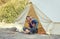 Family glamping outdoor vacation. Mother and her toddler son sitting near big camping tent with cozy interior. Luxury travel