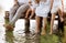 Family group active having fun by the lake. Young mother, father and two cute child daughter girls sitting on wooden