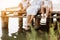 Family group active having fun by the lake. Young mother and two cute child daughter girls sitting on wooden bridge and