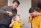 Family haircut at home during quarantine, domestic hairdressers. Father cuts his son hair, mother worried and can`t look at this.