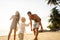 Family happily walk along a tropical beach at sunset