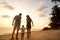 Family happily walk along a tropical beach at sunset