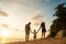 Family happily walk along a tropical beach at sunset