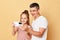 Family with happy facial expression father and daughter wearing casual t-shirts standing isolated over beige background using