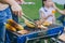 Family happy meal outdoors backyard party BBQ grilled. Roasted meat and corn bread cooking at barbecue stove closeup