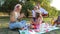 A family has fun during a picnic, mother plays with her daughter and father plays the guitar