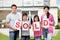 Family holding a sold sign outside their home