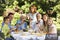 Family Holding Wine Glasses At Table In Back Yard