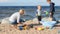 Family holiday on the beach - a young woman with her sons playing with sand.