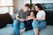 Family at home reading a book. Adult brother and sister reading a book to little sister. Young parents and daughter