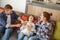 Family at home sitting on couch in living room together parents tickling son playful