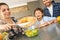 Family at home standing in kitchen together mother adding cutted bell pepper to salad smiling cheerful close-up