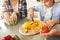 Family at home standing in kitchen together son close-up cutting bell pepper happy helping parents