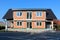 Family house under construction made of red building blocks with new doors and windows and unusual roof surrounded with gravel and