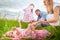 A family including two young parents and daughters on a walk in a meadow with grass and flowers. Dad, mom, girls relaxing and