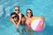 Family with inflatable ball in outdoor swimming pool on sunny summer day
