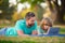 Family, leisure and people concept. Happy father and son with tablet pc computer laying on grass. Kid with daddy