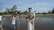 Family, leisure and people concept-young active parents with three daughters enjoying barefoot in water on beach