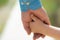 Family. Little child holding hands with his father outdoors, closeup. Family time. Closeup of two touching hands of
