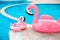 Family look. Two Pink pool floats flamingo by blue water, pool party toy. Giant Inflatable Swimming Ring. Summer vacation holiday