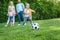 family looking at little boy playing with soccer ball