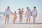 Family, love and beach with a girl, grandparents and parents walking on the sand with a view of the sea or ocean and sky