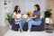 Family and love concept - daughter giving present and flowers to her mother in living room