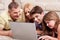 Family lying on carpet in living room with laptop