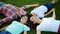 Family lying in circle on grass outdoors. Parents and children holding hands