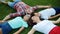 Family lying on green grass in circle. Cute kids and parents relaxing in field