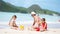 Family making sand castle at tropical white beach. Father and two girls playing with sand on tropical beach