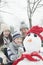 Family making snowman in a park in winter