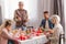 Family members sitting at table and grandfather holding cutlery