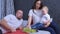 Family mom, dad and baby girl are eating grapes together at home in bed.