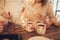 Family: mom, dad and daughter in white sweaters cook and drink cocoa with marshmallows. Closeup hands and cups. Christmas concept