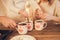 Family: mom, dad and daughter in white sweaters cook and drink cocoa with marshmallows. Closeup hands and cups. Christmas concept