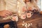 Family: mom, dad and daughter in white sweaters cook and drink cocoa with marshmallows. Closeup hands and cups. Christmas concept