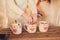 Family: mom, dad and daughter in white sweaters cook and drink cocoa with marshmallows. Closeup hands and cups. Christmas concept