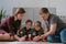 Family mom, dad and two twin brothers draw together markers and felt pens sitting on the floor.