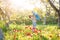 Family mom with daughter woman with child in spring stand and hug on a glade with green grass and tulips