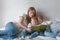 Family mom and two twin brothers toddlers read books laying on the bed. Family reading time.