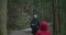 A family, mother and 2 children, a young girl in a red jacket and a young boy in a green jacket,  walk a forest path