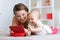 Family - mother and baby with tablet on floor at home. Woman and child girl relaxing at tablet computer.