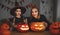 family mother and child daughter in costumes and makeup to halloween with pumpkin in dark