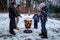 Family with mother and children at a campfire grilling hot dog food. Winter snow outdoor scene.
