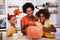 Family mother and children prepare for Halloween. They are carving pumpkin