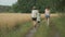 Family mother and children two daughters walking together along country road, back view