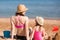 family mother and daughter in bikinis and hats sit on seashore. vacation with kids