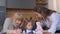 The family of mother, grandmother and daughter are painting with colored paints on the kitchen table