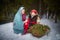 Family with mother and little daughter in stylized medieval peasant clothing in winter forest. The woman and child pose